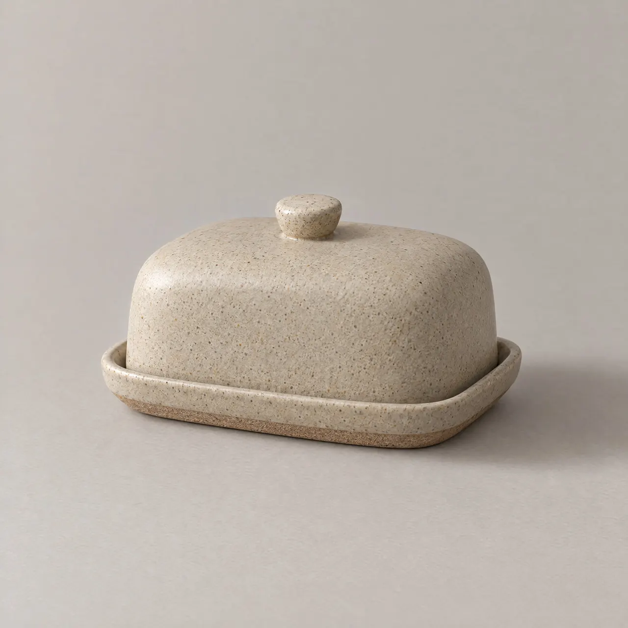 Beurrier en grès émaillé sable avec sa cloche, vu de trois quarts sur fond gris clair