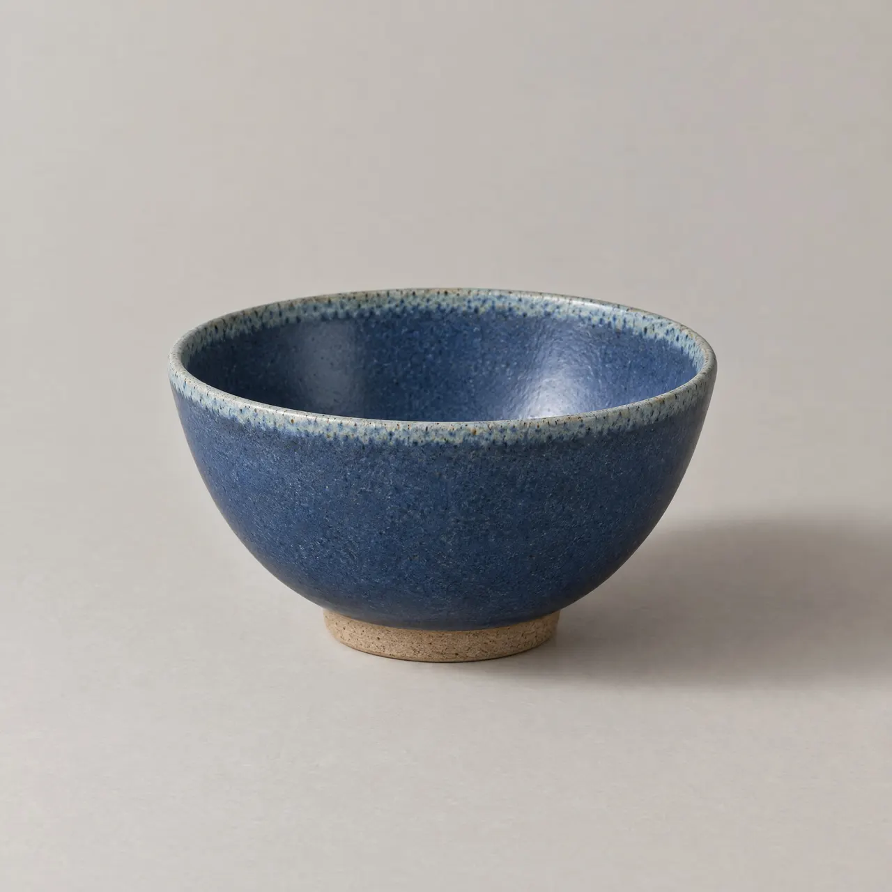 Bol en grès émaillé bleu vu de trois quarts sur fond gris clair
