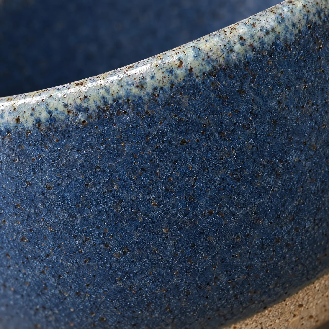 Détail de l'émail bleu moucheté, du bord clair et du pied en grès brut