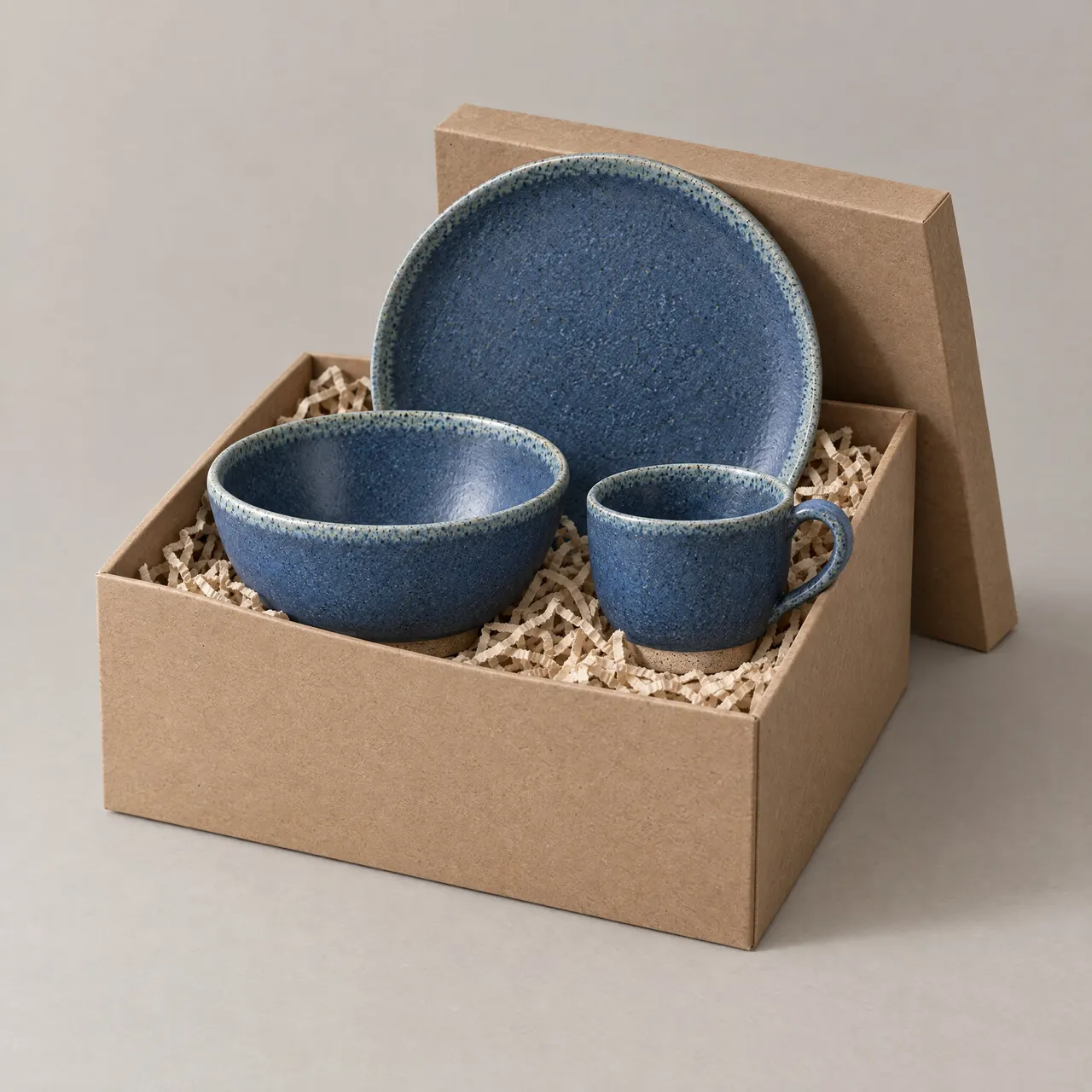 Coffret découverte grès ouvert, bol, tasse et assiette bleus dans leur boîte, sur fond gris clair