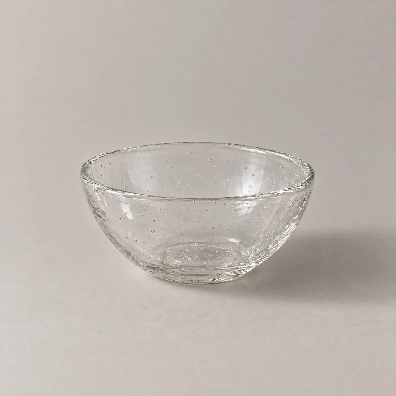 Coupelle en verre soufflé transparent vue de trois quarts sur fond gris clair