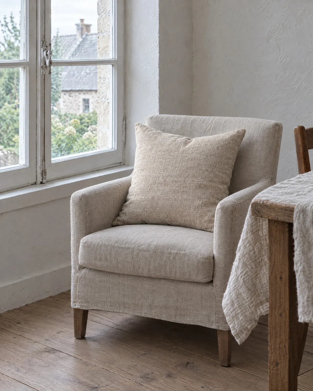 Coussin en lin lavé posé dans un fauteuil près d'une fenêtre