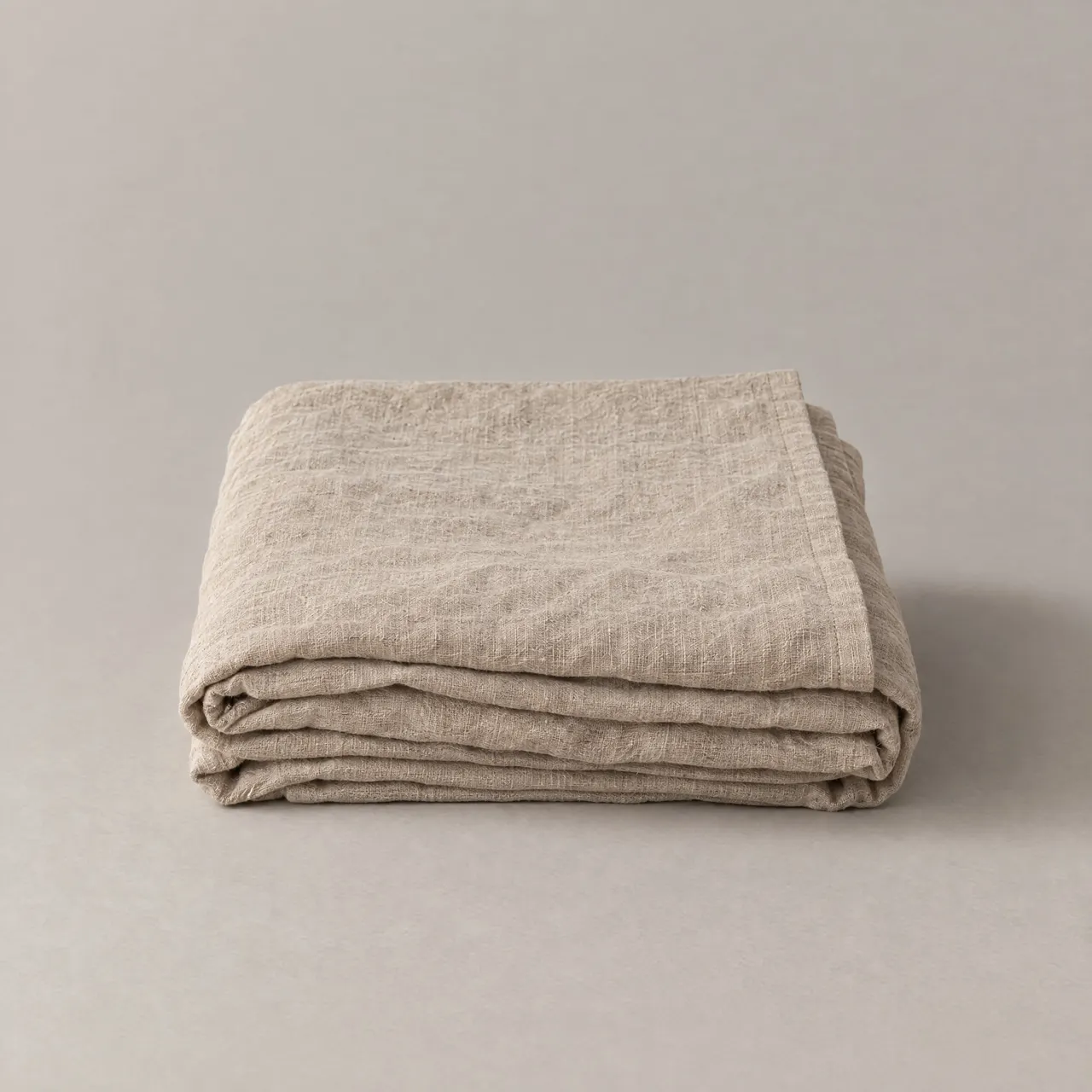 Nappe en lin naturel pliée en carré sur fond gris clair