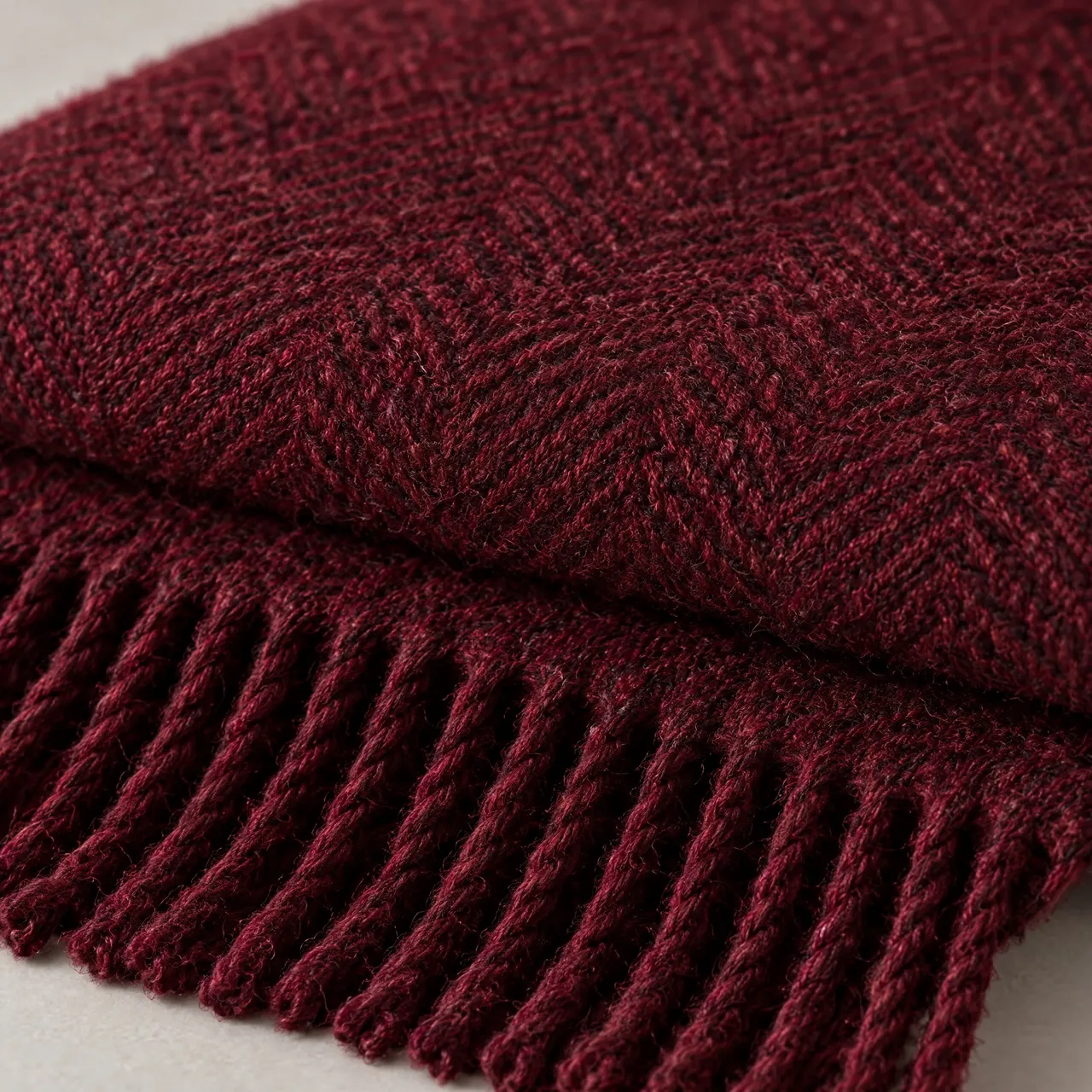 Détail du tissage à chevrons de la laine grenat et des franges torsadées