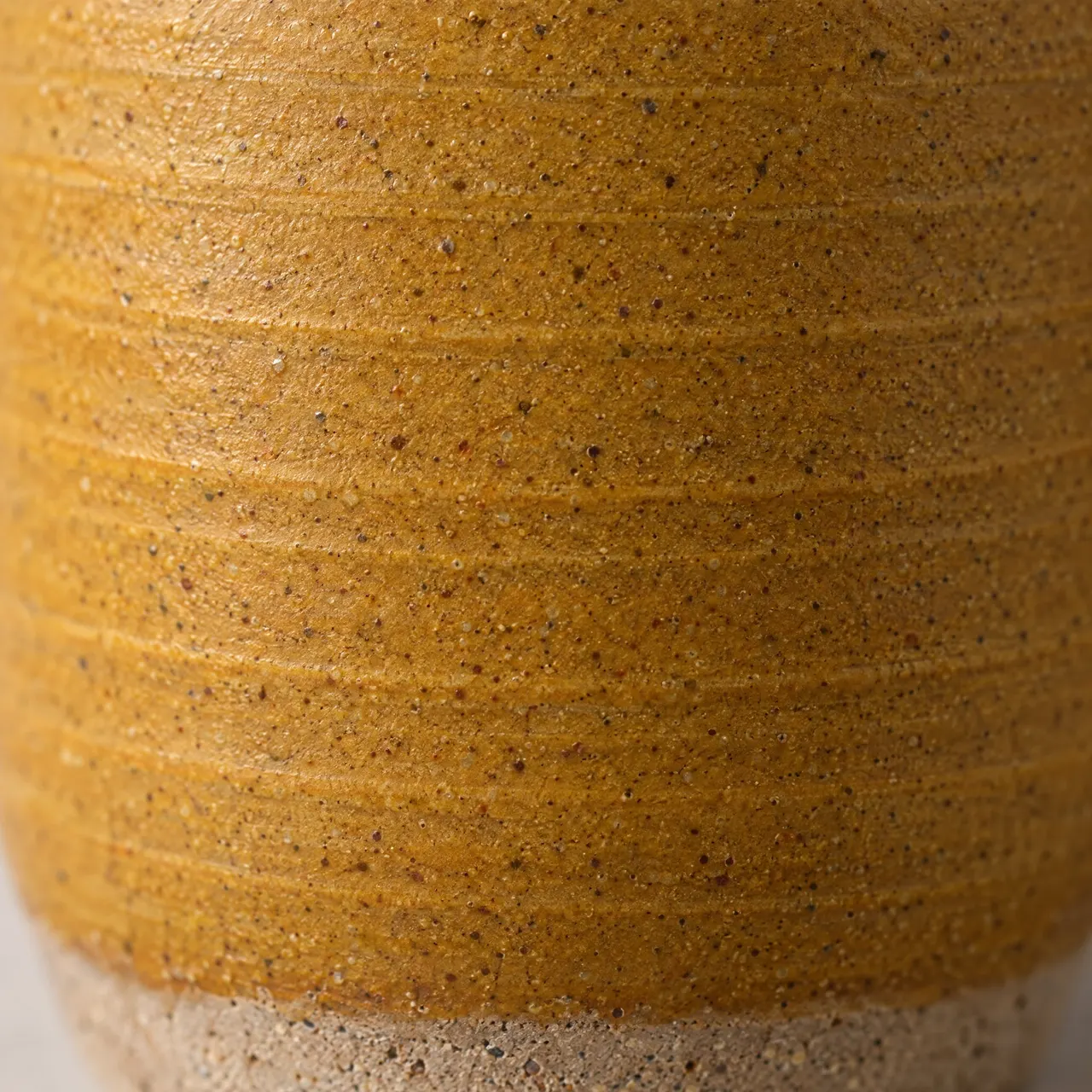 Détail de l'émail ocre moucheté, des traces de tournage et du pied en grès brut