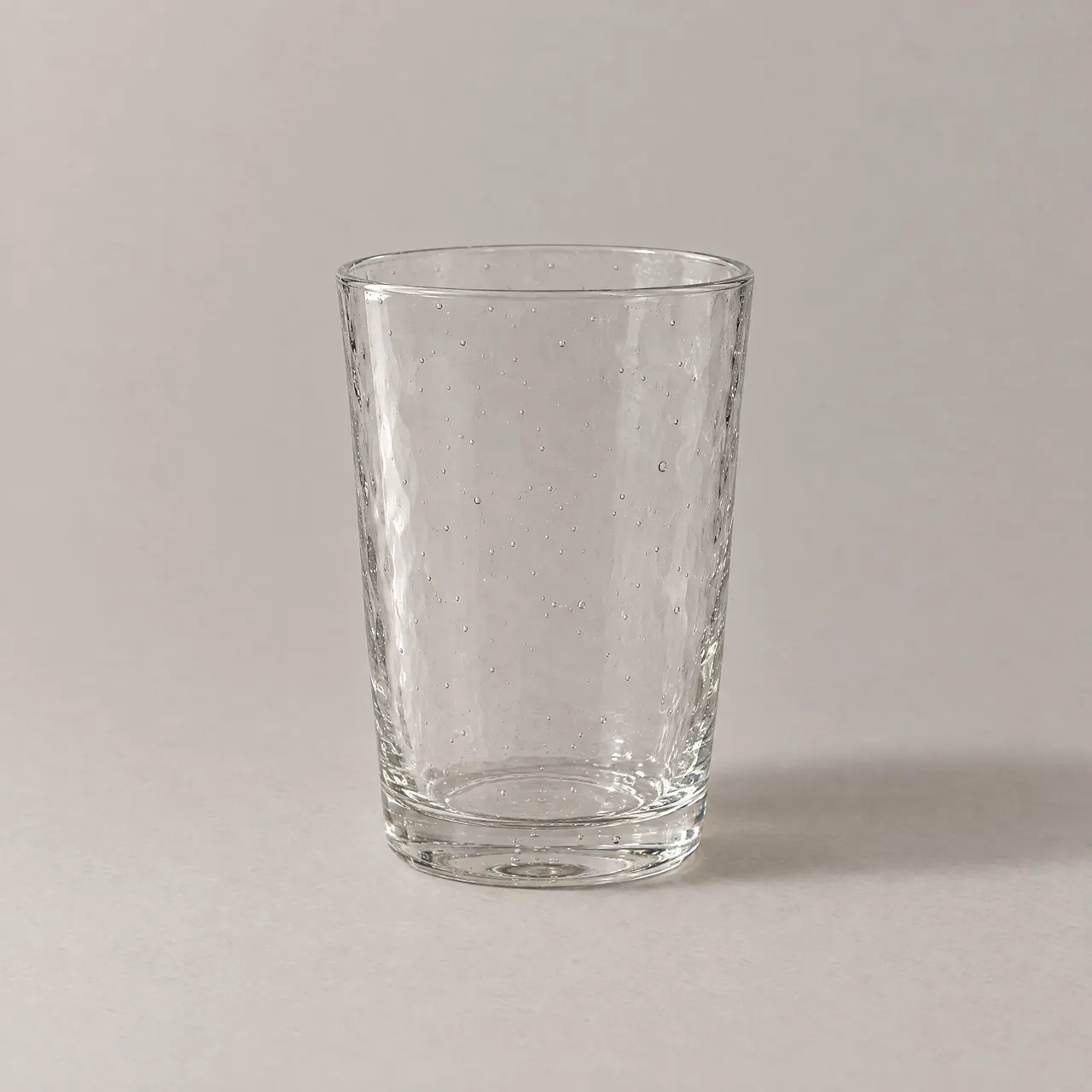 Verre à eau en verre soufflé transparent vu de face sur fond gris clair